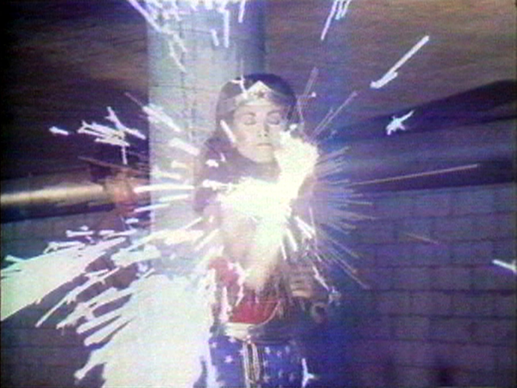 Dara Birnbaum, Technology/Transformation: Wonder Woman: the superhero with closed eyes, light bursting from her hands, a still from the series