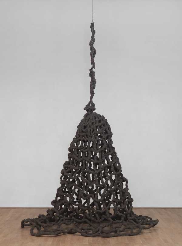Pino Pascali, Trappola: a large dark brown net of steel wool hanging from the ceiling on a cable and spreading across a wooden floor